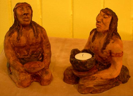 Figurines de deux Innus assis par terre. Leurs bras et mains sont r�alis�s de mani�re � tenir une bougie de type ex-voto.