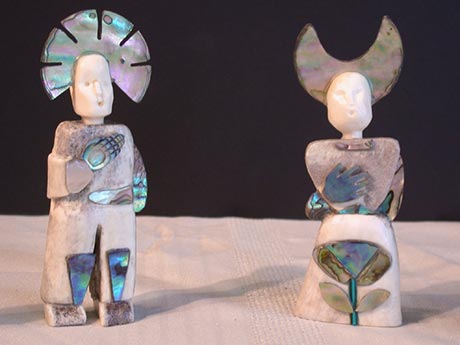 Les deux personnages représentés ici ont environ 3 pouces de haut. Ce sont Klooskombe qui est le principal héros mythique de la culture Wabanaki et Nogami qui est l'ancêtre de Klooskombe. J'ai représenté Klooskombe jeune avec la forme d'un soleil de nacre sur la tête. Il porte sa main droite sur son coeur. Nogami serre également sa main droite sur son coeur. Elle porte une coiffe en forme de lune.